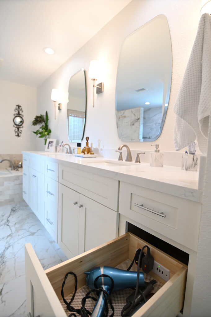White shaker double vanity with quartz countertop, oval mirrors, and built-in appliance drawer in master bathroom in Moorpark by RnD Builders Inc