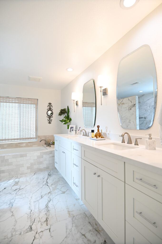 Moorpark bathroom remodel: Bright master bathroom with white shaker vanity, dual sinks, and marble-look porcelain tile flooring in Moorpark by RnD Builders Inc