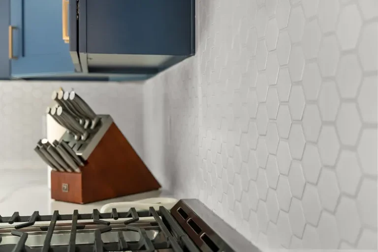 White hexagon tile backsplash with navy blue cabinets and gas range cooktop in Thousand Oaks by RnD Builders Inc