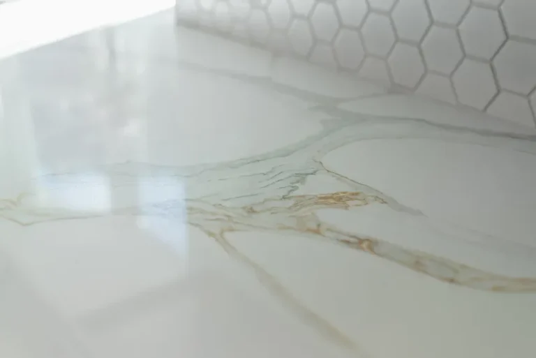 Thousand Oaks home transformation: Close-up of polished white marble surface with gold veining and hexagonal tile backsplash in Thousand Oaks by RnD Builders Inc