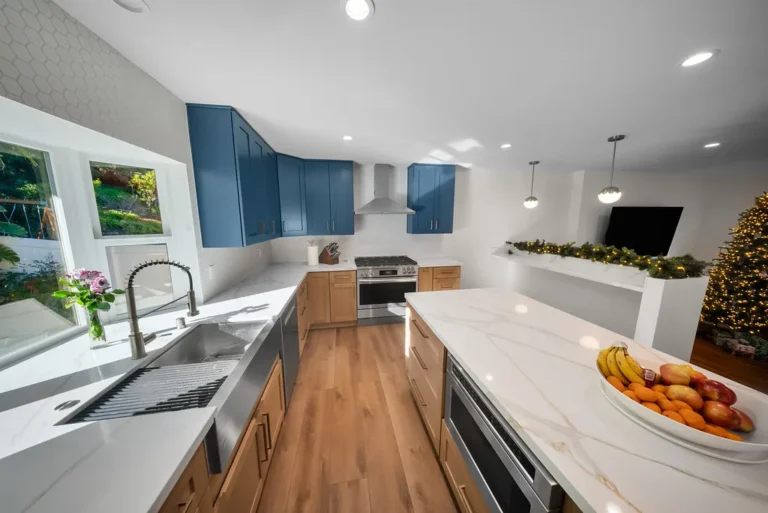 Modern kitchen with blue upper cabinets, natural wood lower cabinets, and white quartz countertops in Thousand Oaks by RnD Builders Inc