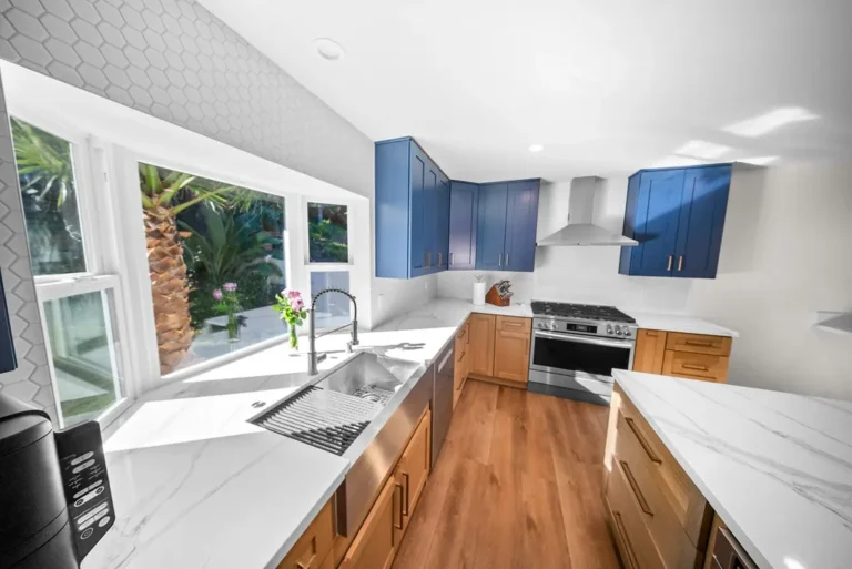 Thousand Oaks home transformation: Modern kitchen with blue upper cabinets, natural wood lower cabinets, and white quartz countertops in Thousand Oaks by RnD Builders Inc