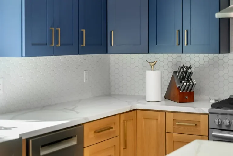 Thousand Oaks home transformation: Two-tone kitchen with navy upper cabinets, natural wood lower cabinets, white marble countertops, and hexagon tile backsplash in Thousand Oaks by RnD Builders Inc