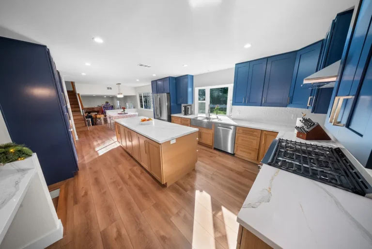 Open-concept kitchen with navy blue shaker cabinets, natural wood island, and quartz countertops in Thousand Oaks by RnD Builders Inc
