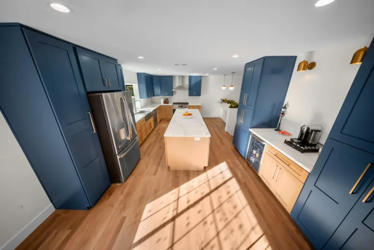 Spacious kitchen with navy blue shaker cabinets, natural wood base cabinets, and white quartz island in Thousand Oaks by RnD Builders Inc