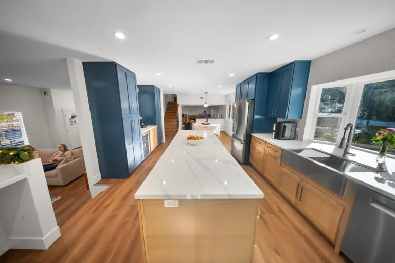 Thousand Oaks home transformation: Open-concept kitchen with navy shaker cabinets, quartz waterfall island, and stainless farmhouse sink in Thousand Oaks by RnD Builders Inc