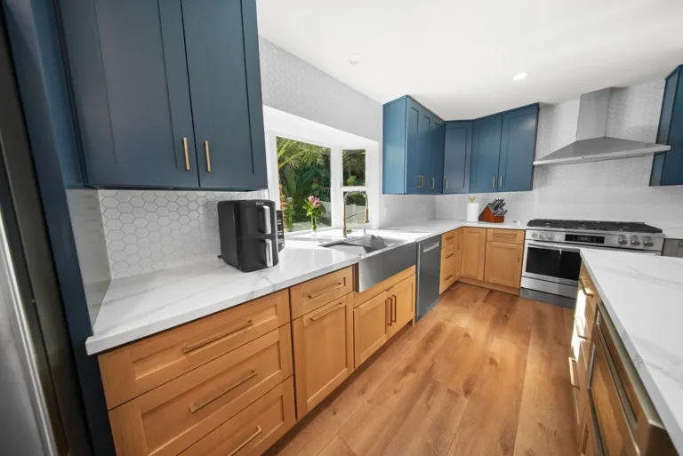 Two-tone kitchen with navy upper cabinets, natural wood lower cabinets, quartz countertops, and stainless steel appliances in Thousand Oaks by RnD Builders Inc