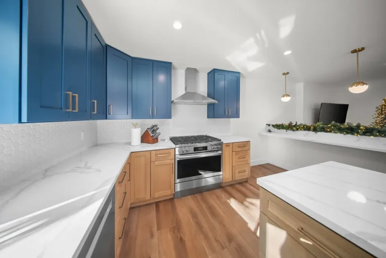 Thousand Oaks home transformation: Modern kitchen with navy blue upper cabinets, natural wood lowers, stainless range, and white quartz countertops in Thousand Oaks by RnD Builders Inc