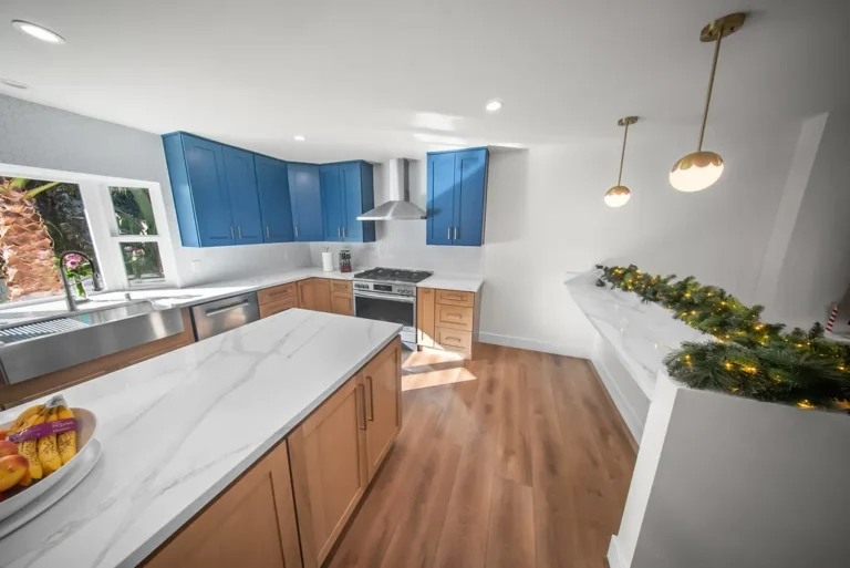 Two-tone kitchen with blue shaker upper cabinets, natural wood base cabinets, and white marble island in Thousand Oaks by RnD Builders Inc