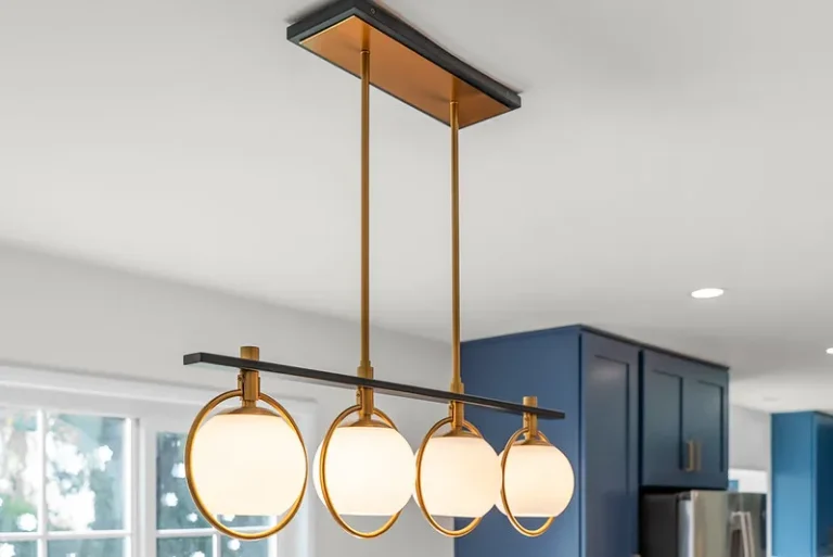 Gold and black four-globe pendant light fixture over kitchen with navy blue cabinets in Thousand Oaks by RnD Builders Inc