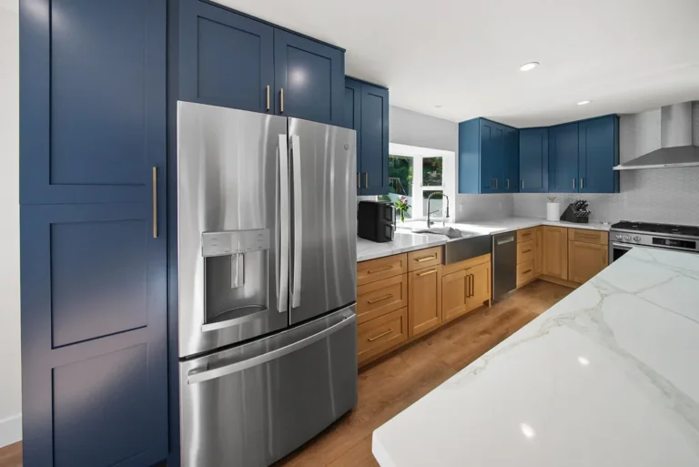 Two-tone kitchen with navy shaker cabinets, natural wood base cabinets, and stainless steel French door refrigerator in Thousand Oaks by RnD Builders Inc