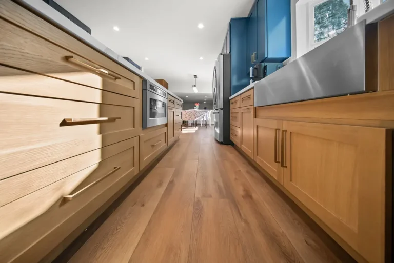 Thousand Oaks home transformation: Galley kitchen with light oak shaker cabinets, blue upper cabinets, and wide-plank hardwood floors in Thousand Oaks by RnD Builders Inc