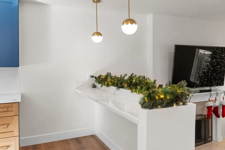 Thousand Oaks home transformation: Open-concept kitchen with white quartz peninsula, blue upper cabinets, and brass globe pendant lights in Thousand Oaks by RnD Builders Inc