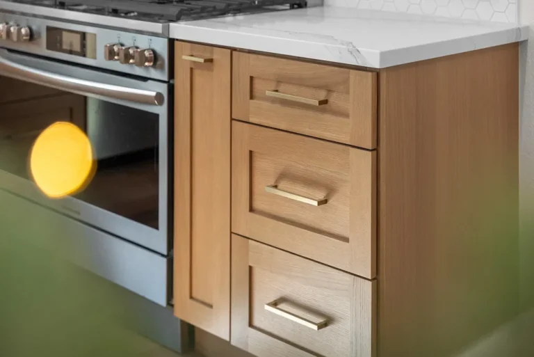 Natural oak shaker cabinets with brass pulls and marble countertop beside stainless steel range in Thousand Oaks by RnD Builders Inc