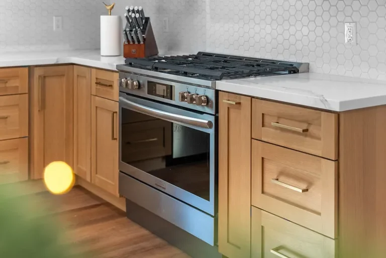 Thousand Oaks home transformation: Natural wood shaker cabinets with stainless steel range and white hexagon tile backsplash in Thousand Oaks by RnD Builders Inc