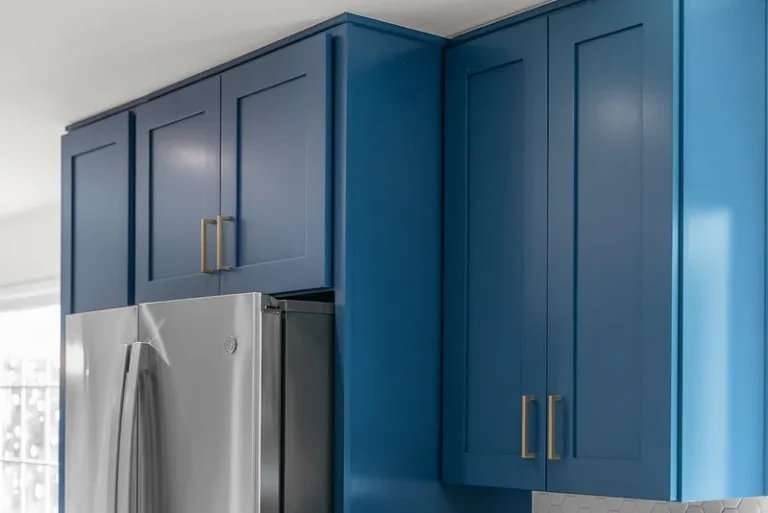 Navy blue shaker-style upper kitchen cabinets with brass hardware and stainless steel refrigerator in Thousand Oaks by RnD Builders Inc