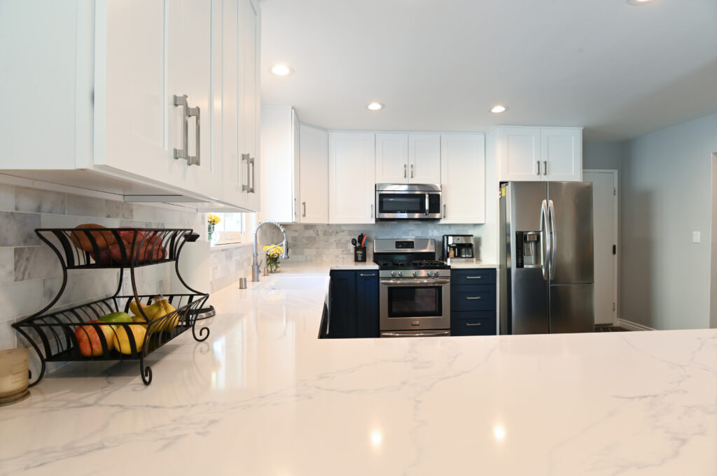 Two-tone kitchen with white upper cabinets, navy lower cabinets, quartz countertops, and stainless steel appliances in Thousand Oaks by RnD Builders Inc