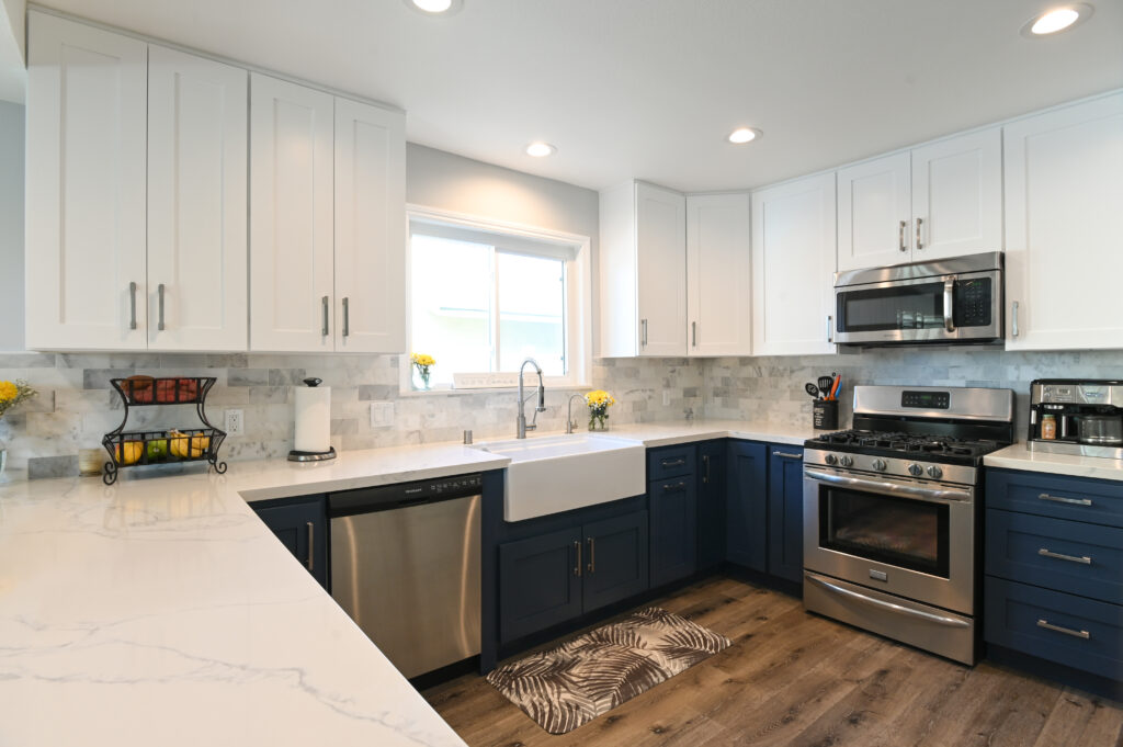 Thousand Oaks navy kitchen: Two-tone kitchen with white upper cabinets, navy lower cabinets, farmhouse sink, and stainless steel appliances in Thousand Oaks by RnD Builders Inc