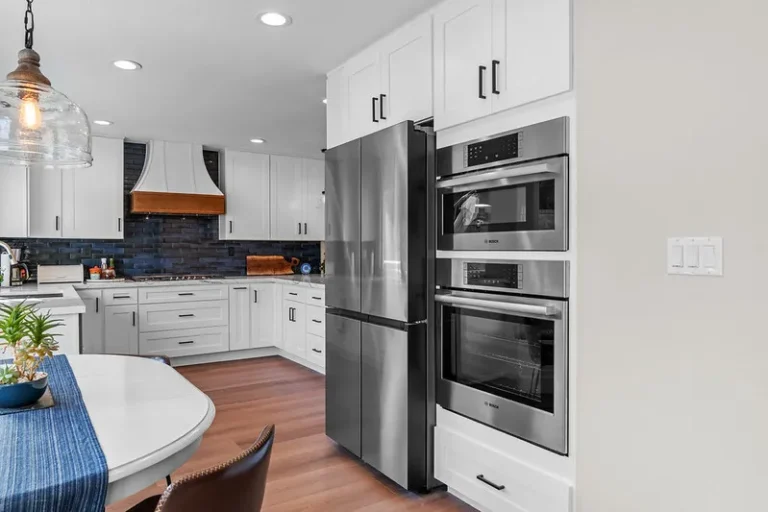 White shaker kitchen with stainless Bosch appliances, navy tile backsplash, and wood range hood in Moorpark by RnD Builders Inc