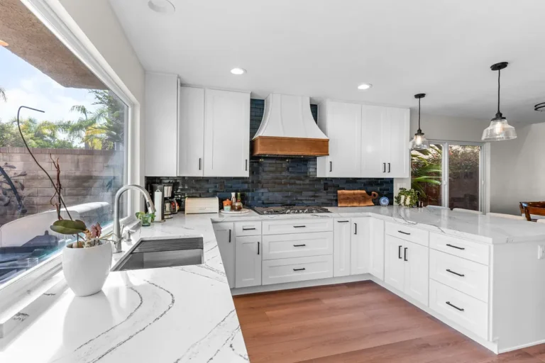 Bright white shaker kitchen with quartz countertops, copper range hood, and dark subway tile backsplash in Moorpark by RnD Builders Inc
