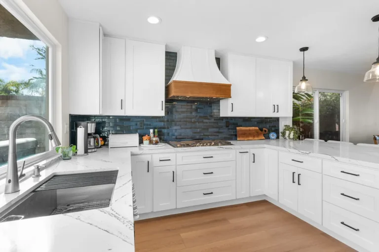White shaker kitchen with quartz countertops, blue tile backsplash, and wood range hood in Moorpark by RnD Builders Inc