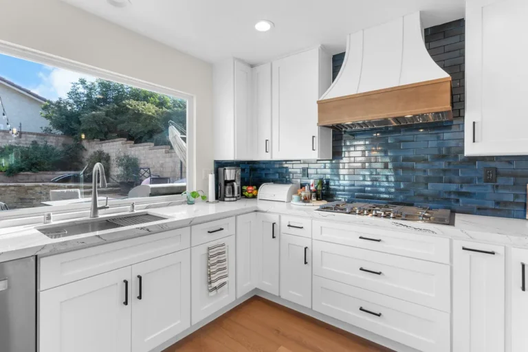 White shaker kitchen with blue subway tile backsplash and wood-accented range hood in Moorpark by RnD Builders Inc