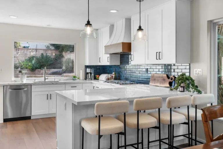 White shaker kitchen with blue subway tile backsplash, quartz island, and pendant lights in Moorpark by RnD Builders Inc