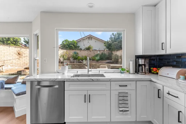 White shaker cabinet kitchen with quartz countertops, stainless sink, and garden window view in Moorpark by RnD Builders Inc