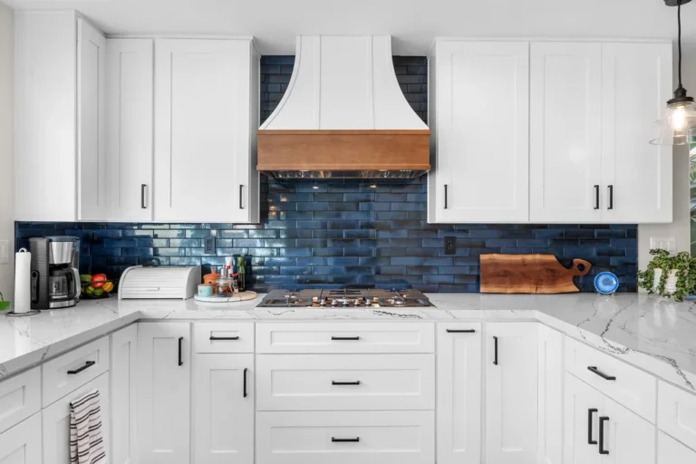 White shaker kitchen with navy blue subway tile backsplash and wood-accented range hood in Moorpark by RnD Builders Inc