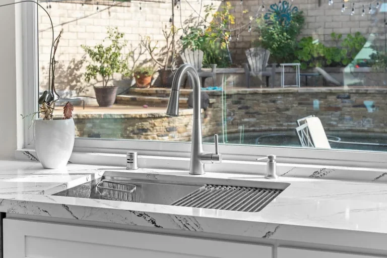 White quartz countertop with undermount stainless steel sink and pull-down faucet overlooking backyard in Moorpark by RnD Builders Inc