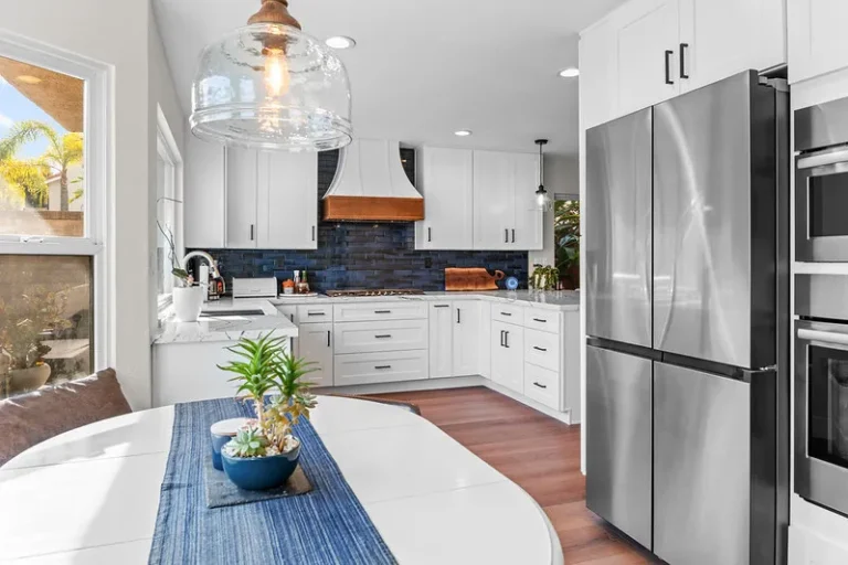 Bright white shaker kitchen with navy blue tile backsplash and stainless steel appliances in Moorpark by RnD Builders Inc