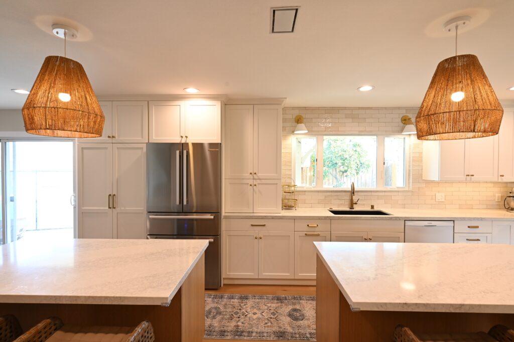 Bright White Shaker Kitchen with Dual Quartz Islands in Thousand Oaks Bright white shaker kitchen with dual quartz islands, stainless refrigerator, and woven rattan pendant lights in Thousand Oaks by RnD Builders Inc