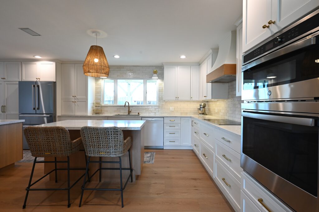 Bright White Shaker Kitchen with Quartz Island in Thousand Oaks Bright white shaker kitchen with quartz island, woven pendant lights, and stainless double wall ovens in Thousand Oaks by RnD Builders Inc