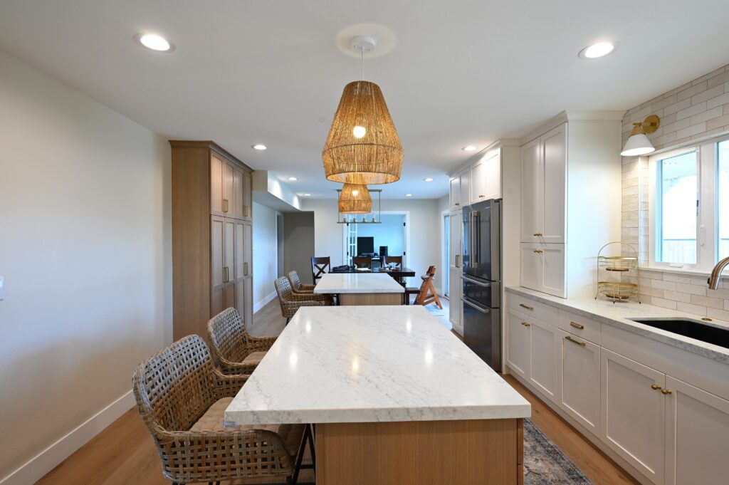 Open-concept Kitchen with Quartz Island in Thousand Oaks Open-concept kitchen with quartz island, white shaker cabinets, and woven pendant lights in Thousand Oaks by RnD Builders Inc