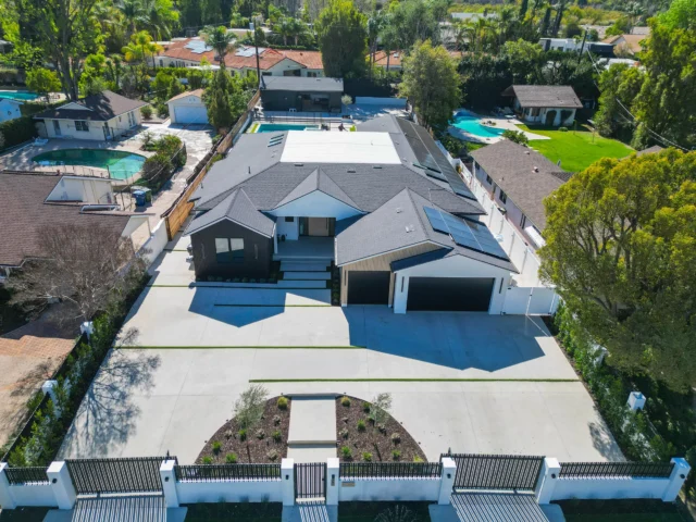 Aerial View of Modern Custom Home with Dark Siding Aerial view of modern custom home with dark siding, three-car garage, and pool by RnD Builders Inc