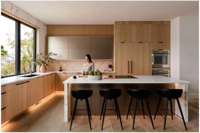 Modern Open Kitchen with White Oak Flat-panel Cabinets Modern open kitchen with white oak flat-panel cabinets, marble backsplash, and waterfall island by RnD Builders Inc