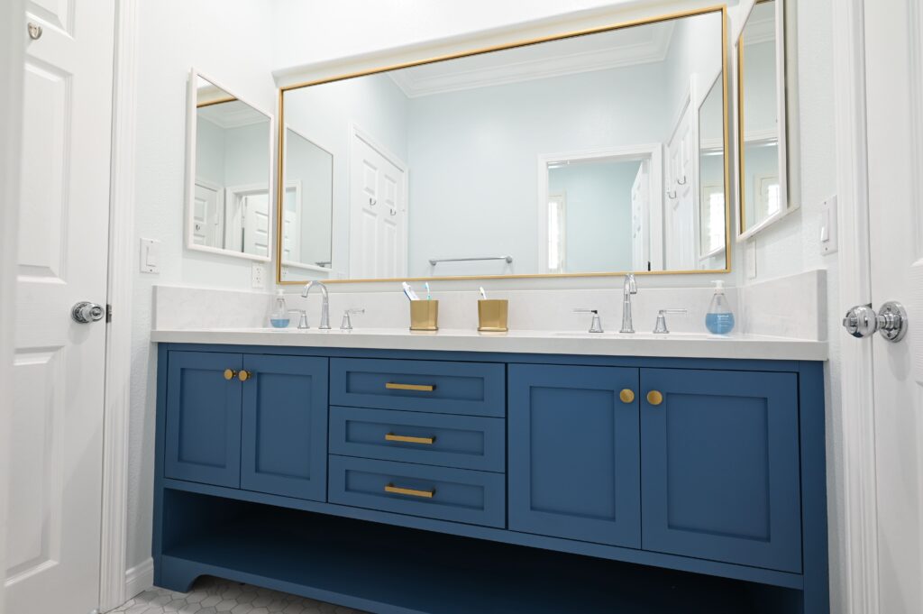 Thousand Oaks Bathroom Remodel Double-sink bathroom vanity with navy blue shaker cabinets, gold hardware, and white quartz countertop in Thousand Oaks by RnD Builders Inc