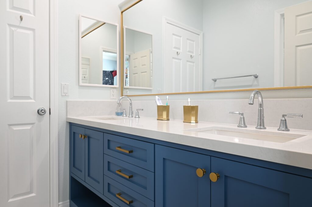 Newbury Park Bathroom Remodel Double-sink bathroom vanity with navy blue shaker cabinets, white quartz countertop, and gold hardware in Thousand Oaks by RnD Builders Inc