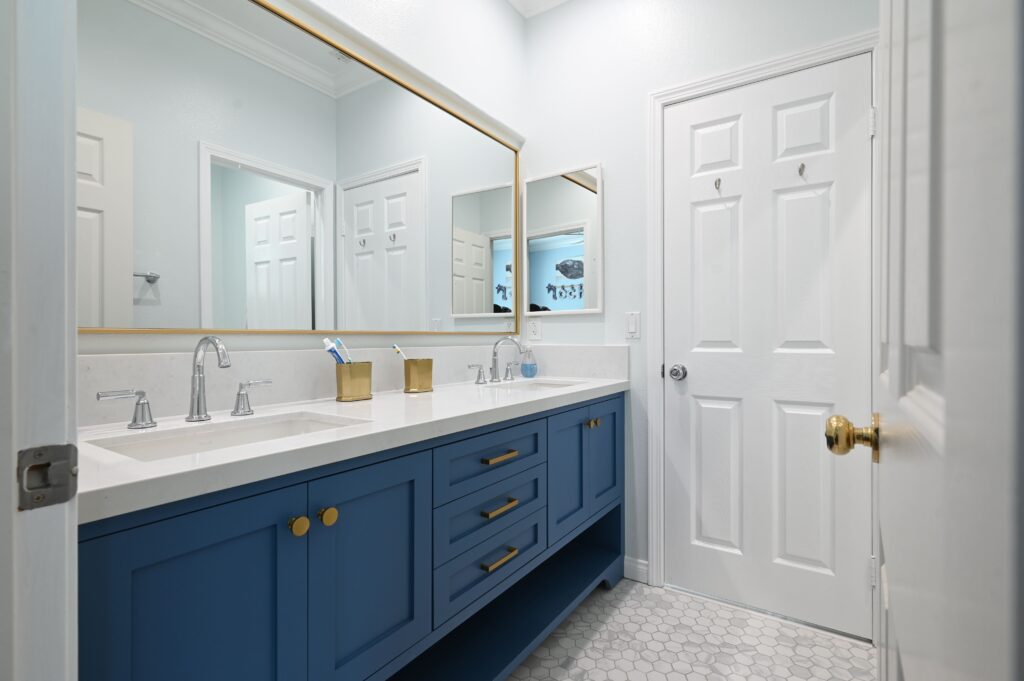 Newbury Park bathroom remodel: Double-sink bathroom vanity with navy blue shaker cabinets, white quartz countertop, and gold hardware in Newbury Park by RnD Builders Inc