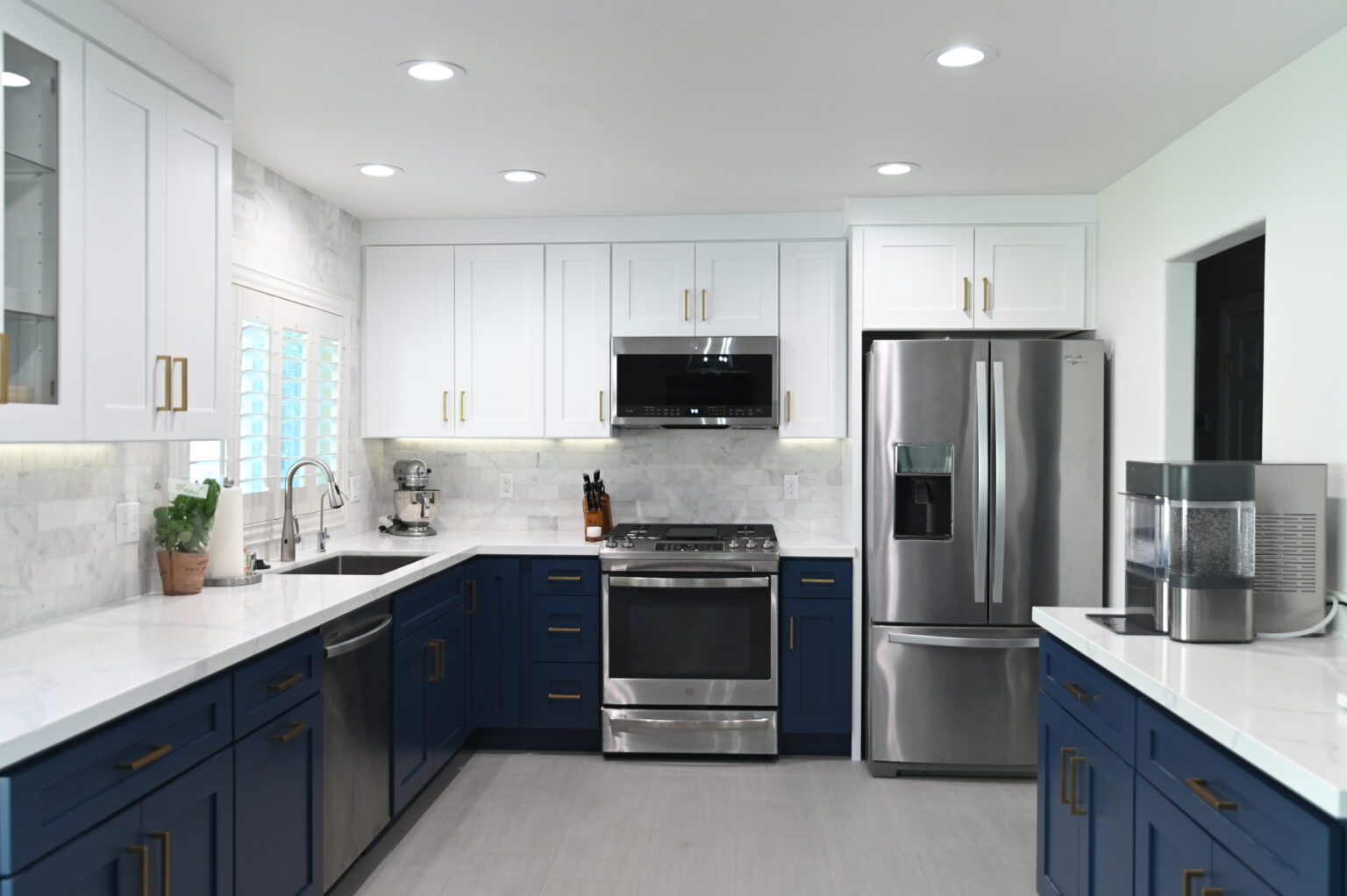 Two-tone kitchen with navy lower cabinets, white upper cabinets, and stainless steel appliances by RnD Builders Inc