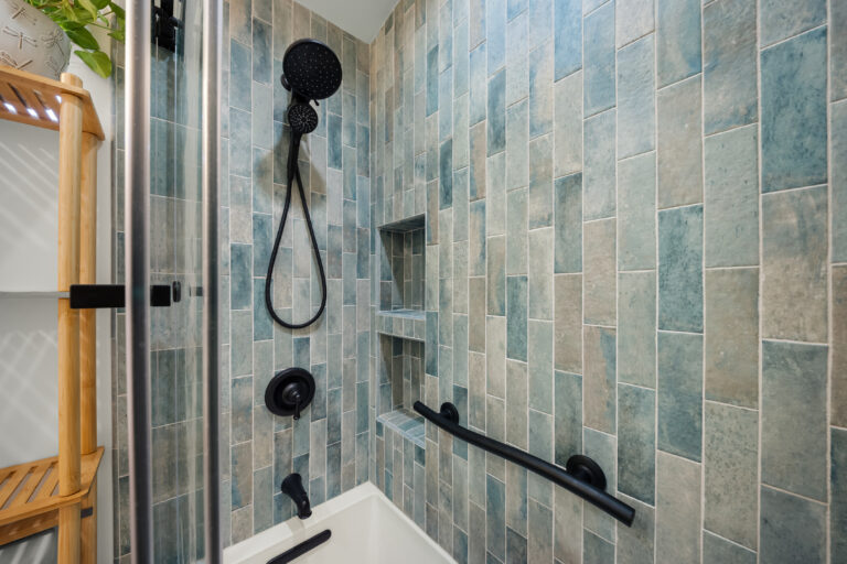 ADU Shower Wall with Handheld and Niche with blue vertical tile, black fixtures, a niche and a grab bar in Simi Valley by RnD Builders Inc