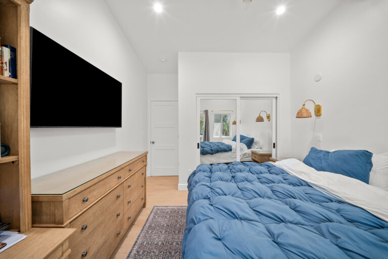 ADU Bedroom Dresser and TV Wall with a wood dresser, a wall-mounted TV and a mirrored wardrobe in Simi Valley by RnD Builders Inc