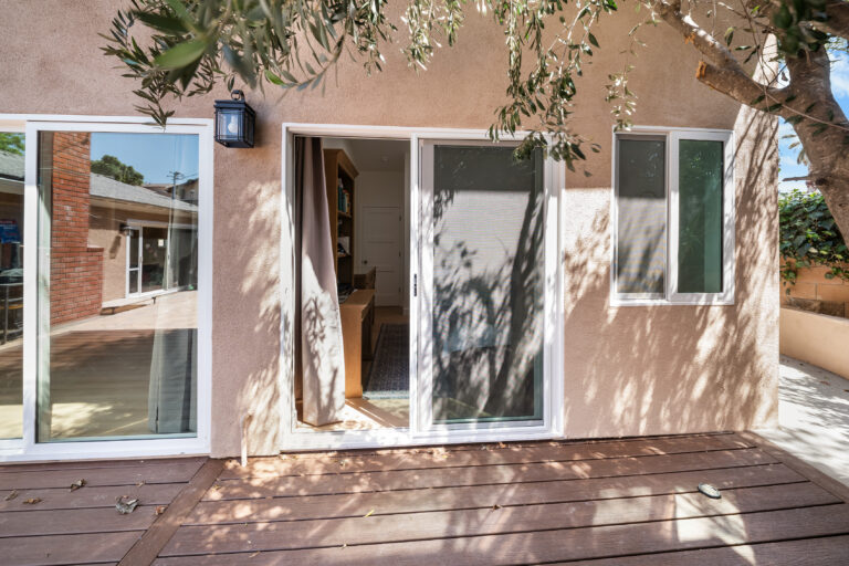 ADU Deck and Stucco Exterior with a wood deck, sliding glass doors and stucco walls beneath a mature tree in Simi Valley by RnD Builders Inc