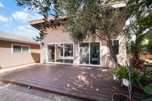simi-valley-adu-construction-by-rnd-builder-image-43 Rear wood deck with sliding glass doors on stucco home surrounded by mature trees by RnD Builders Inc