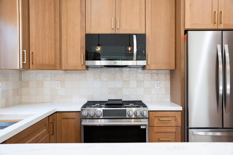 ADU Kitchen Backsplash and Microwave with wood cabinets, a stainless microwave and range, and a tile backsplash in Simi Valley by RnD Builders Inc