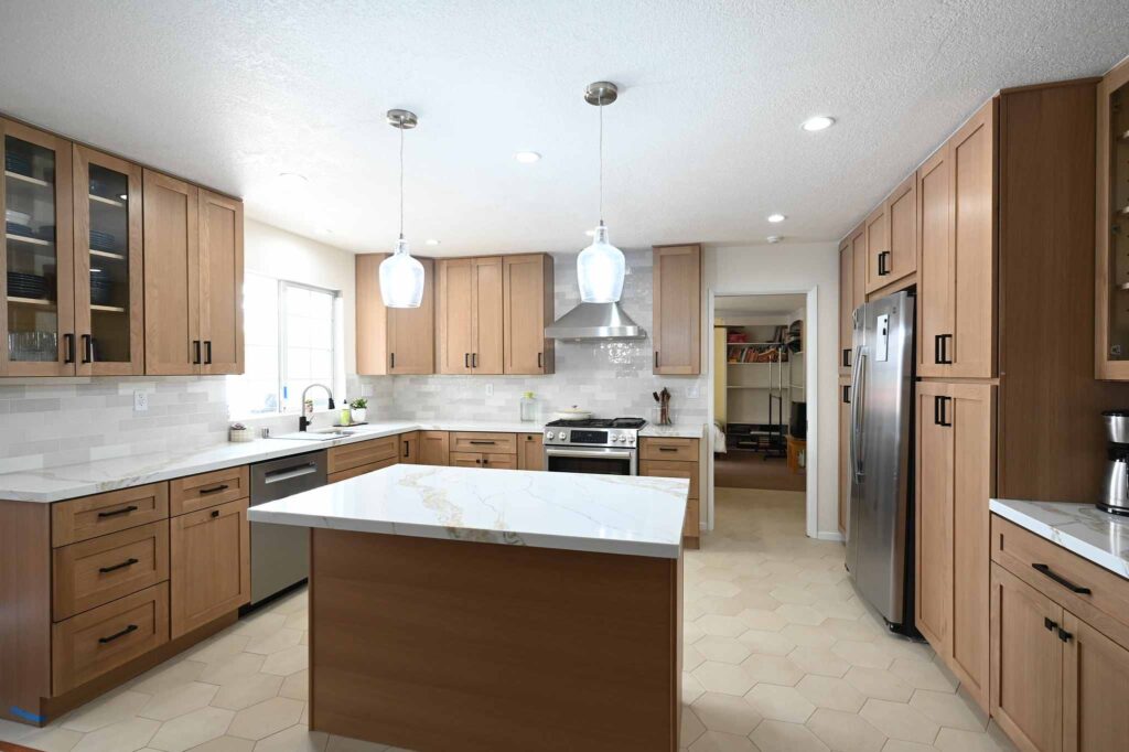 Spacious kitchen remodel with warm oak shaker cabinets, quartz island, and herringbone tile floor in Simi Valley by RnD Builders Inc