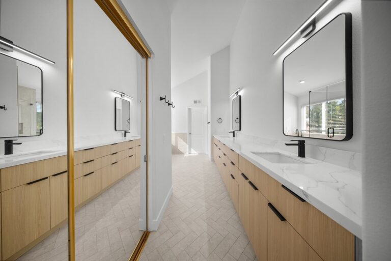 Thousand Oaks bathroom remodel: Dual vanity primary bathroom with light oak cabinetry, white quartz countertops, and herringbone tile floor in Thousand Oaks by RnD Builders Inc