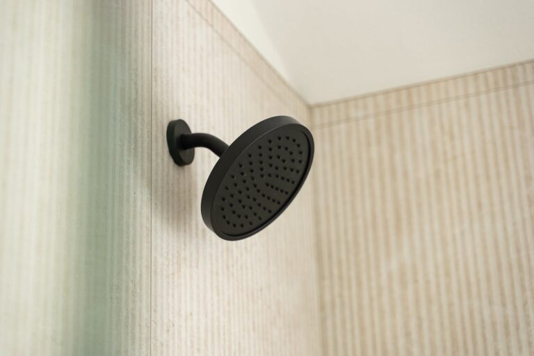 Thousand Oaks bathroom remodel: Matte black round rain showerhead mounted on ribbed neutral tile wall in Thousand Oaks by RnD Builders Inc
