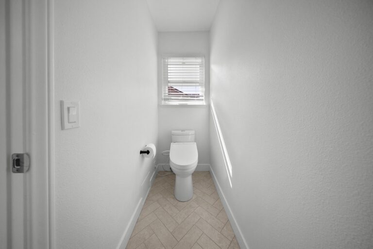 Narrow white water closet with herringbone tile floor and bidet toilet by RnD Builders Inc