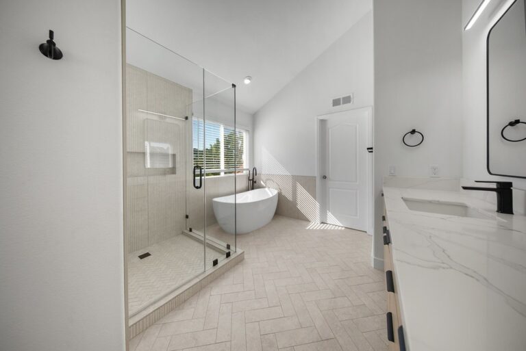 Thousand Oaks bathroom remodel: Luxury primary bathroom with freestanding soaking tub, glass shower, and herringbone tile flooring in Thousand Oaks by RnD Builders Inc